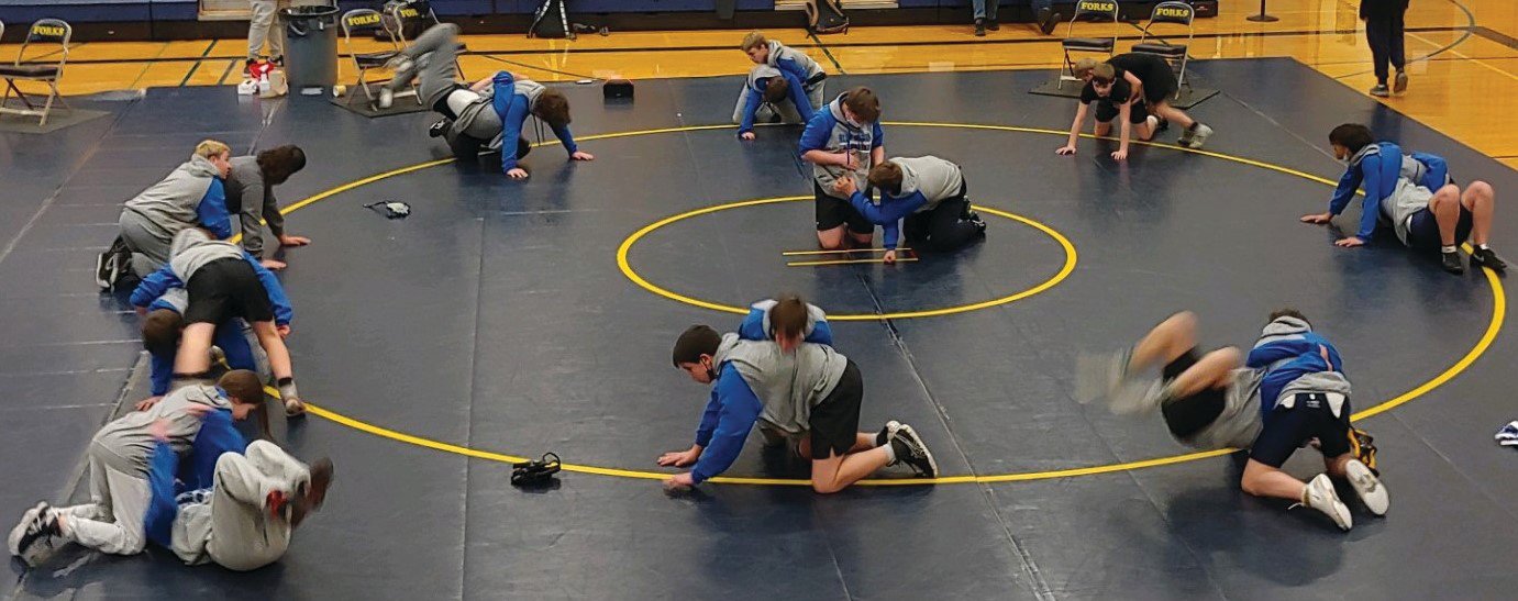 All 20 competing middle school athletes warm up prior to their Olympic League Middle School wrestling meet in Forks Wednesday, March 9. The wrestlers are completing an exercise called “gut wrenches.” To complete this exercise these athletes literally flip over their partner by grabbing onto their sweatshirt near the stomach and flipping over onto their feet, then return to their starting position by flipping over again.